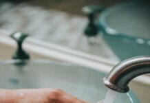 감기 걱정 없는 겨울을 위한 건강 관리 팁 person holding stainless steel faucet