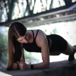 A woman in a black top is doing a push up