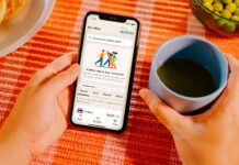 AI 건강 코치의 시대 — 앱이 당신의 ‘헬스 트레이너’가 된다 Hands holding smartphone with app, coffee cup, and food.