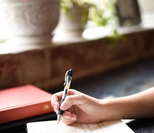 만성피로, 일상 속 작은 변화로 극복할 수 있을까? a person writing on a piece of paper with a pen