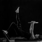 woman in black pants and black boots lying on black wooden bench