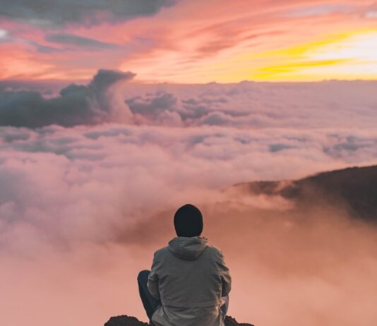 바쁜 일상 속 웰니스 문화, 작은 변화로 건강한 삶 만들기 man sitting on cliff