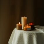 three lit candles sitting on a white table cloth