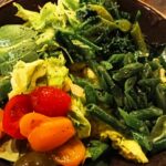 a brown bowl filled with vegetables on top of a wooden table
