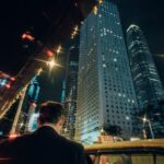 Man in suit enters taxi with city skyscrapers at night