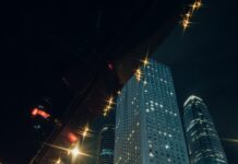 “현대인의 스트레스, 일상 속 작은 습관으로 건강하게 관리한다” Man in suit enters taxi with city skyscrapers at night