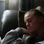 boy in gray hoodie lying on black leather couch