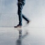 person wearing blue denim jeans beside gray wall