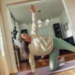 A woman does a yoga pose on a mat.