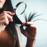 Woman examining split ends of hair with magnifying glass