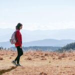 a man with a backpack walking across a dry grass covered field