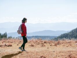일상 속 ‘마음챙김 걷기’, 건강과 힐링을 한 번에 a man with a backpack walking across a dry grass covered field
