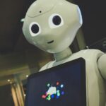 white robot toy holding black tablet