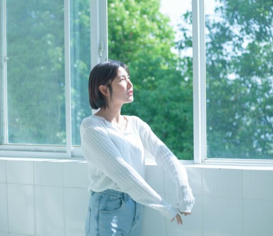 정신건강, ‘작은 습관’에서 시작한다… 일상에서 실천하는 마음 건강법 woman in white long sleeve shirt and blue denim jeans standing by the window